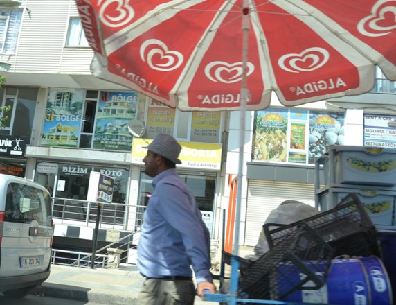 Eskici, güneşten şemsiye ve şapka ile korunuyor